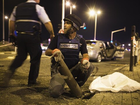 Een Israëlische expert in explosieven van de politie verwijdert de restanten van een raket uit Gaza.