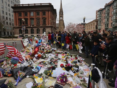 Mensen leggen bloemen en kaarten neer bij een herdenkingsplek in Boston.