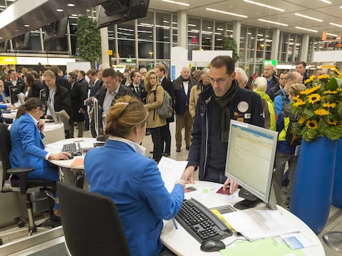 Passagiers staan in de rij om in te checken op Schiphol.