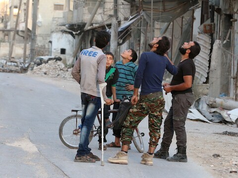 Beducht voor luchtaanvallen speuren mannen de lucht af in het door rebellen gecontroleerde deel van Aleppo.