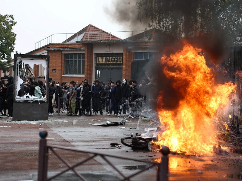 Zwarte rook stijgt op uit brandende vuilnisbakken en fietsen terwijl scholieren een blokkadeactie voeren aan het middelbaar Cesar Baggio in Rijsel. 
