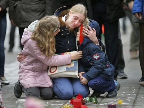 Een vrouw en haar kinderen leggen bloemen neer in Brussel.