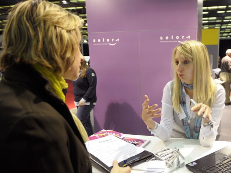 Een vrouw gaat inlichten inwinnen bij de stand van Selor, het selectiebureau voor federale ambtenaren.