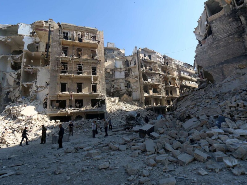 Inwoners van de Al-Chaar-wijk staan te midden van hun vernielde huizen in Aleppo, 30 mei.