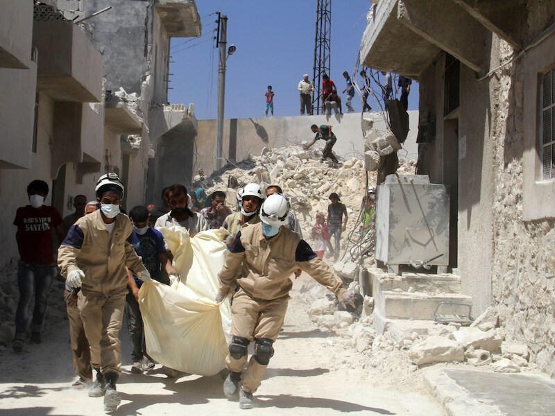 Reddingswerkers dragen het lichaam weg van een slachtoffer van een vermoedelijke luchtaanval van het Syrisch leger, gisteren in Aleppo.