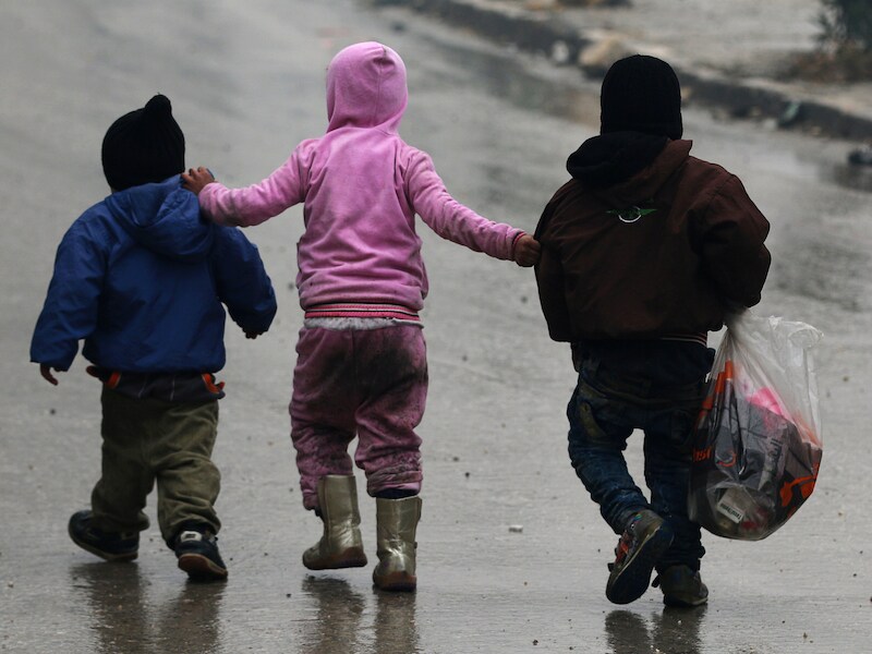 Kinderen stappen samen over straat in Aleppo.
