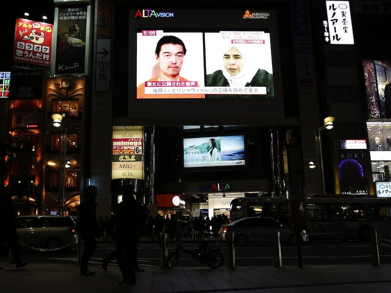Een tv-scherm in Tokio toont een nieuwsprogramma waarin de foto's te zien zijn van de Japanse gegijzelde Goto en de Iraakse terreurverdachte tegen wie hij van IS moet worden uitgeruild.