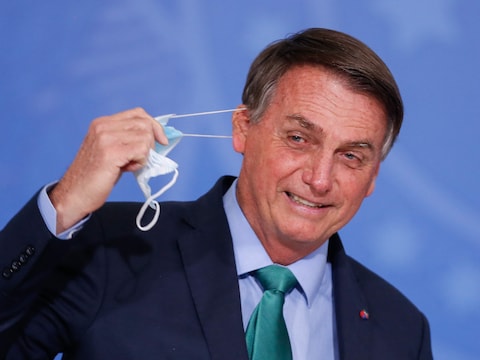 Jair Bolsonaro (66) doet een mondkapje af. De Braziliaanse president bagatelliseert corona en drijft de spot met zieken.