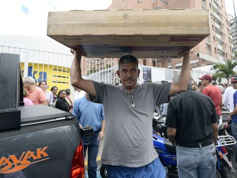 Een man tilt een lcd-tv boven zijn hoofd nadat hij heeft geshopt bij een vestiging van de elektronicaketen Daka in de Venezolaanse hoofdstad Caracas.
