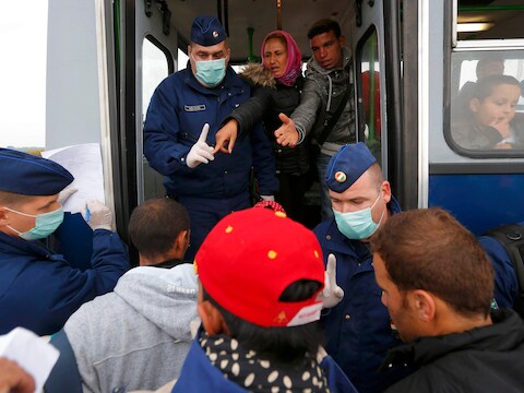 Agenten begeleiden vluchtelingen op een bus in de Roszke, aan de grens met Servië. Tegen begin volgende maand wil Hongarije klaar zijn met de bouw van een hek van prikkeldraad aan de grens.