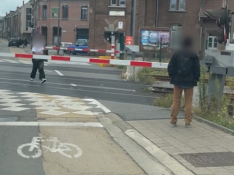 De vrouw steekt de spoorweg over terwijl de slagbomen naar beneden zijn.