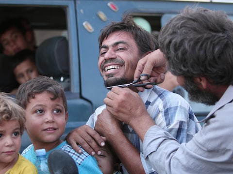Een man knipt de baard van een man die gegijzeld werd door Islamitische Staat. De gijzelaars werden bevrijd door het Vrije Syrische leger.