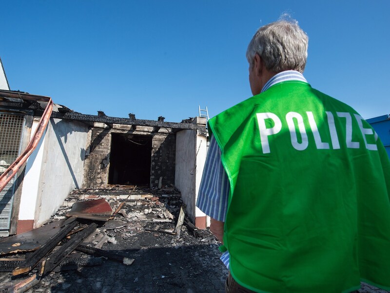 Een onderzoeker van de politie bekijkt de schade aan een onderkomen voor asielzoekers in Reichertshofen.