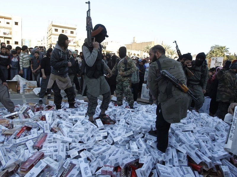 ISIL-aanhangers vernietigen in beslag genomen sigarettenpakken in de Syrische stad Raqqa.