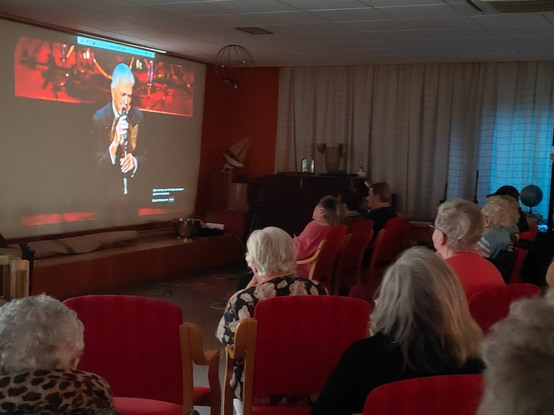 Bewoners genieten van een livestreamconcert van Gene Bervoets, die nummers bracht van Frank Sinatra.