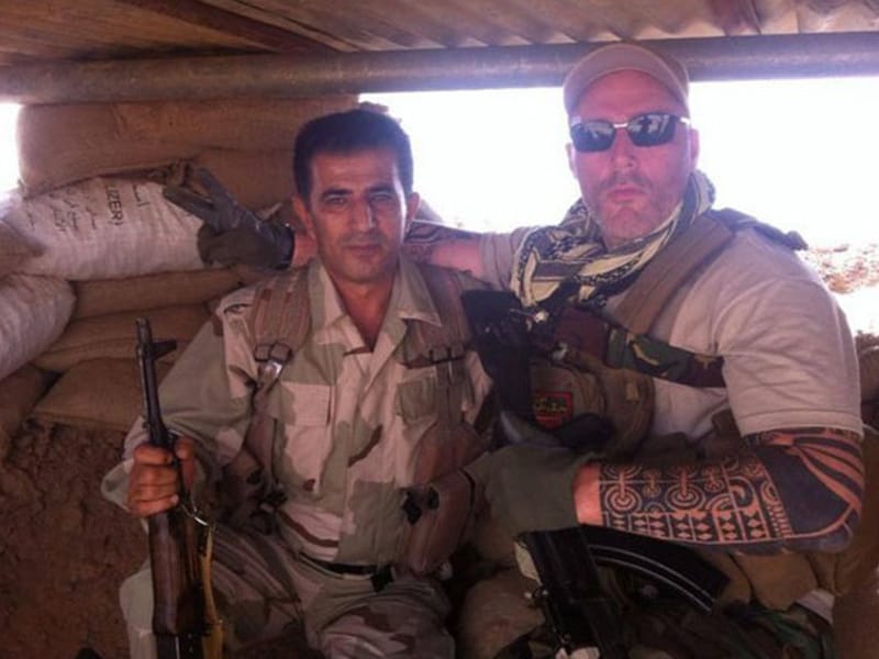 Nederlander Ron (rechts), lid van motorbende No Surrender, poseert naast een Koerdische strijdmakker in een bunker in de buurt van Mosoel.