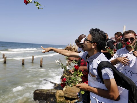 Palestijnen gooien bloemen in zee ter nagedachtenis van de Palestijnse vluchtelingen die vorige week voor de kust van Malta omkwamen.
