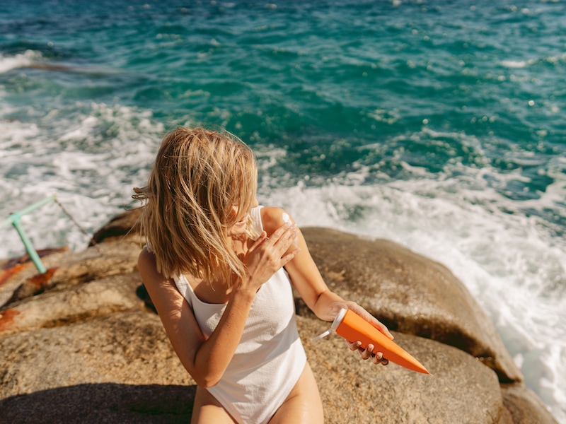 Beeld ter illustratie. Vrouw die zich insmeert met zonnecrème voordat ze de zee ingaat. 