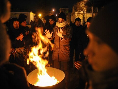 Manifestanten warmen zich op het Mikhaylivskaplein in Kiev.