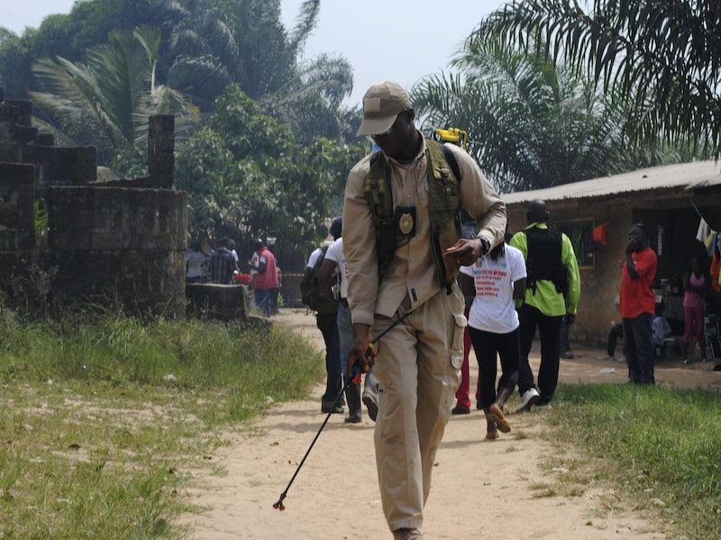Een hulpverlener desinfecteert een weg in het door ebola getroffen Liberia.