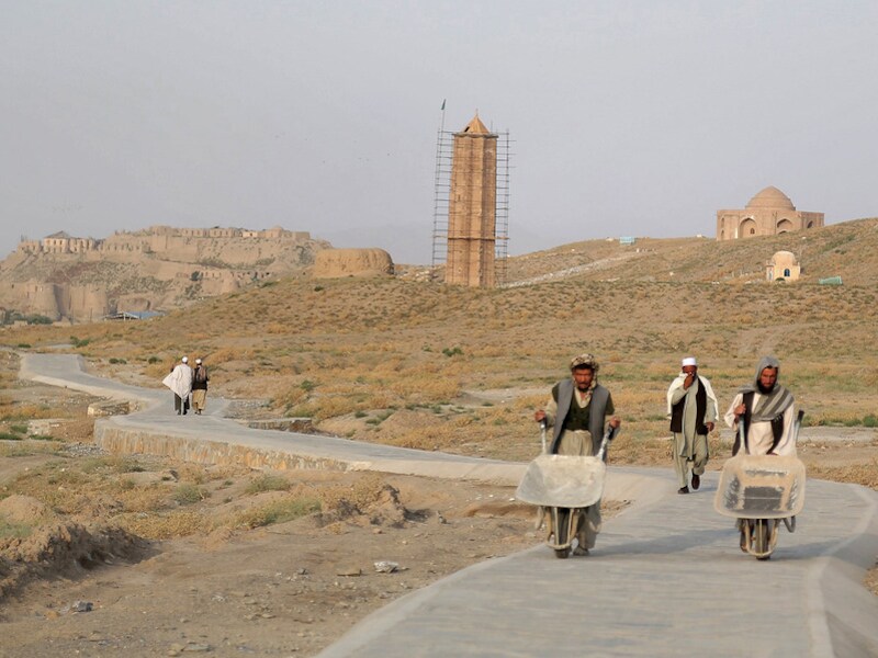 Arbeiders wandelen langs een eeuwenoude minaret in Ghazni.