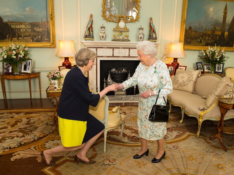 Brits premier Theresa May buigt voor de Queen.