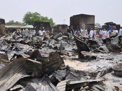 Mensen lopen tussen de door Boko Haram verbande huizen in Gambaru, Nigeria.