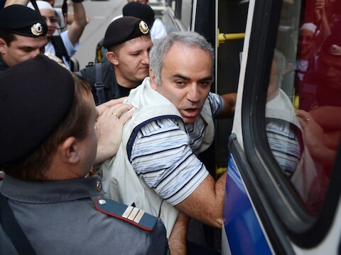 Kasparov wordt een politiebusje ingeduwd.