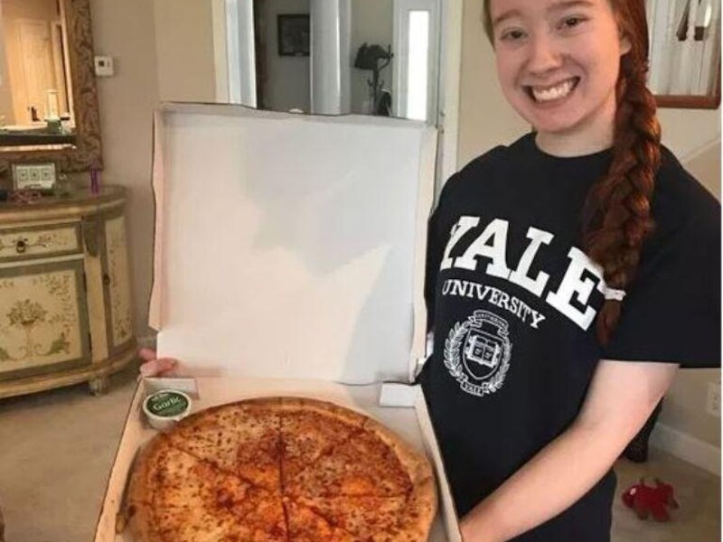 Een trotse Carolina met haar Yale shirtje aan en een pizza van Papa John's.