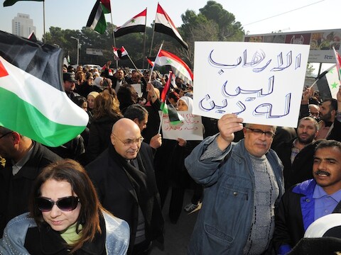 Een betoger houdt een plakkaat omhoog met daarop: "Terrorisme heeft geen godsdienst". Op 15 december zouden voor het hoofdkwartier van de VN in Damascus 32 burgers gedood zijn door de groepering Islamitische Staat.