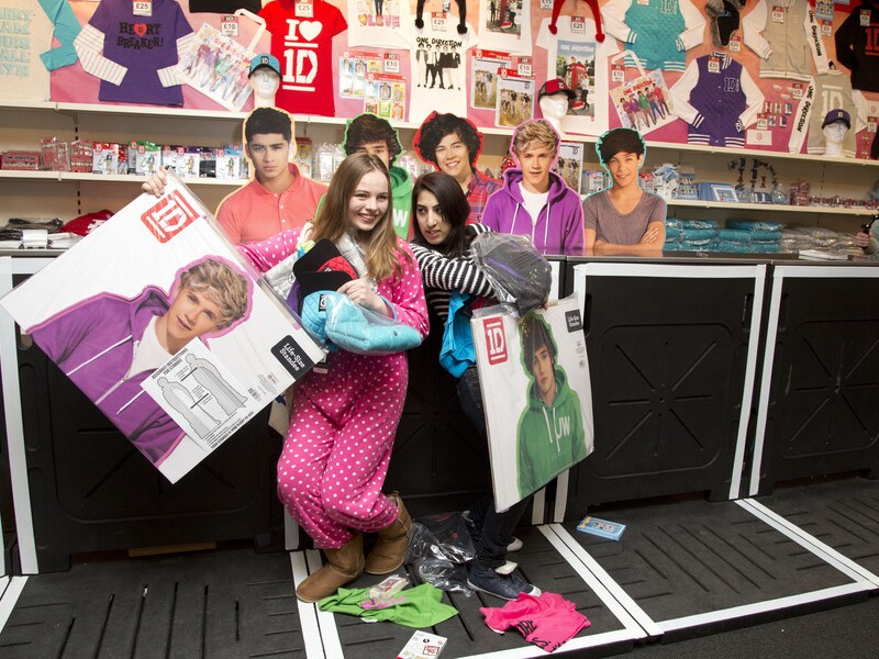 Fans van One Direction in een winkel met merchandise van de groep.