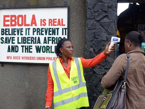 Een beveiliger controleert de temperatuur van een vrouw in Monrovia.