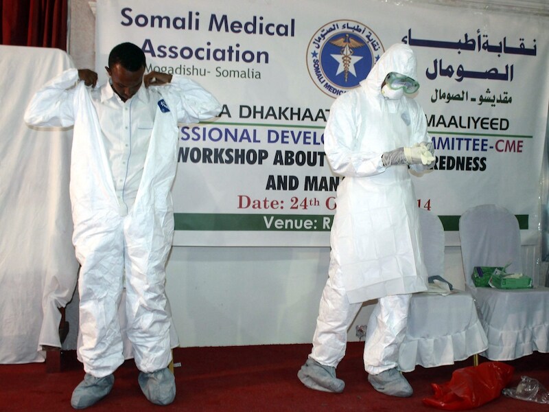 Een man doet in Somalië voor hoe het ebola-pak aangetrokken moet worden.