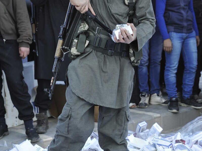 Een strijder van de ISIL (Islamitische Staat in Syrië en de Levant) vernietigt in beslag genomen sigarettenpakken in de stad Raqqa. (archieffoto)
