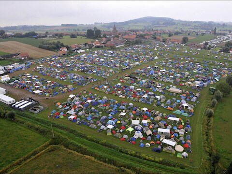 De campingweide van het festival en bovenaan in beeld de kerk van Dranouter, waar het Rode Kruis toegang tot heeft.