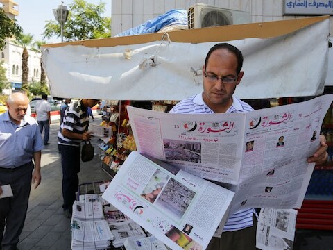 Een man leest een krant in Damascus vandaag.