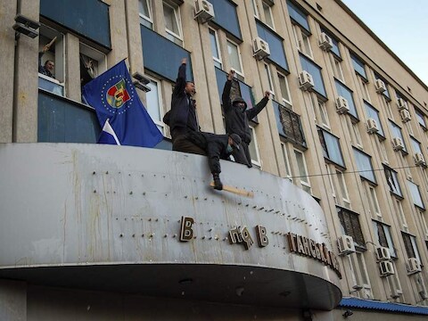 Pro-Russische demonstranten verwijderen het symbool van de staatsveiligheidsdienst in Loehansk.