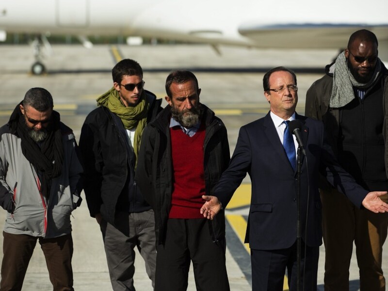President Hollande hield een welkomstspeech voor de vrijgelaten gijzelaars die bij hem staan, eergisteren op een militair vliegveld even buiten Parijs. Marine Le Pen heeft gezegd dat ze verbaasd was over de baard en de kleding van de mannen. .