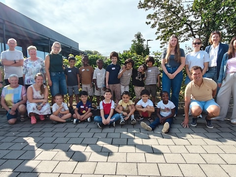 De deelnemende kinderen, samen met begeleiders, samen met de burgemeester en enkele schepenen. 