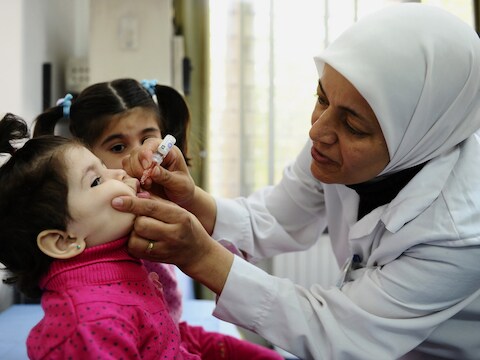Een werknemer van UNICEF dient een Syrisch kind in de hoofdstad Damascus een vaccinatie toe tegen polio.