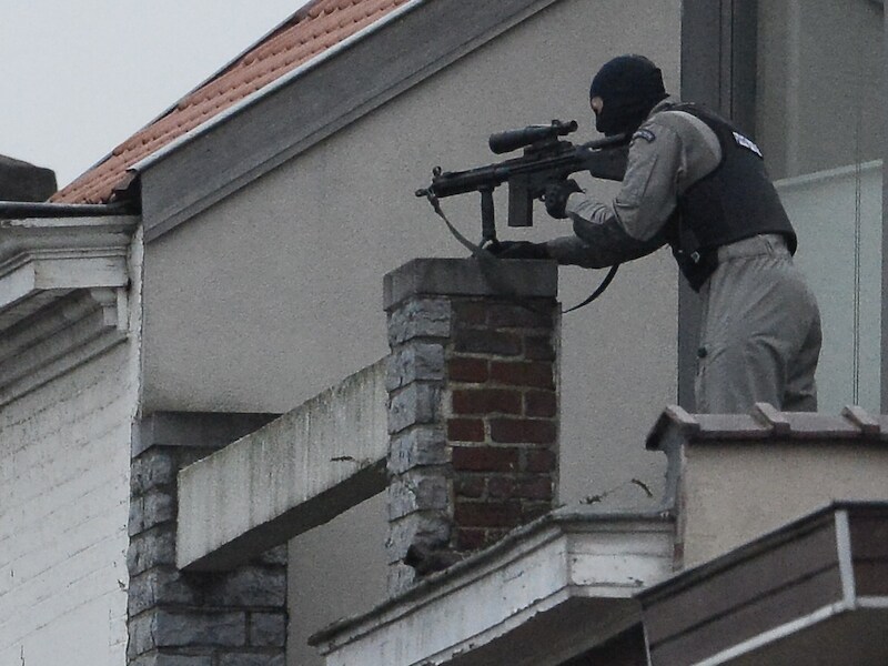 Een lid van de speciale politie-eenheid richt zijn wapen op het 'terreurhuis' in Vorst van waaruit minstens twee verdachten dinsdag het vuur openden op de politie.
