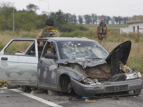 Een Oekraïense soldaat onderzoekt een vernietigde auto bij een checkpoint in de buurt van Donetsk.