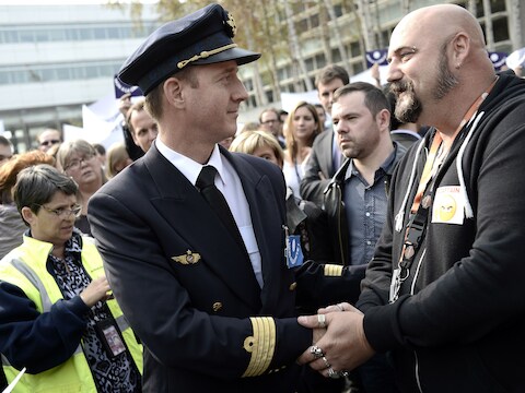 Een werknemer en piloot van Air France schudden elkaar de hand tijdens een staking die gisteren plaatsvond.