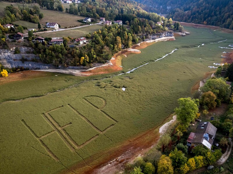 Een luchtfoto toont de reusachtige “HELP” die is aangebracht op de bodem van het Lac des Brenets. 
