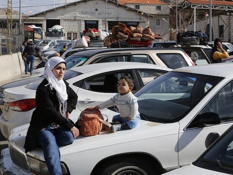 Een Syrische moeder wacht om de grens met Libanon over te steken.