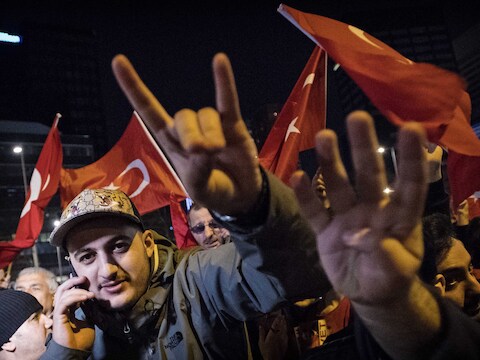 Zaterdagavond 11 maart: een demonstrant aan het Turks consulaat in Rotterdam maakt het teken van de Turkse extreemrechtse organisatie Grijze Wolven.