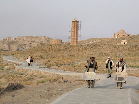 Arbeiders wandelen langs een eeuwenoude minaret in Ghazni.