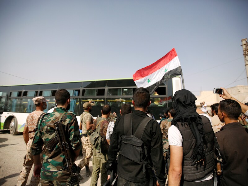 Syrische burgers worden naar de bussen begeleid.