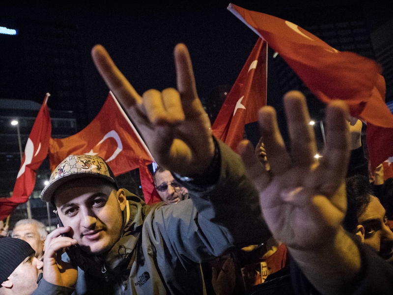 Zaterdagavond 11 maart: een demonstrant aan het Turks consulaat in Rotterdam maakt het teken van de Turkse extreemrechtse organisatie Grijze Wolven.