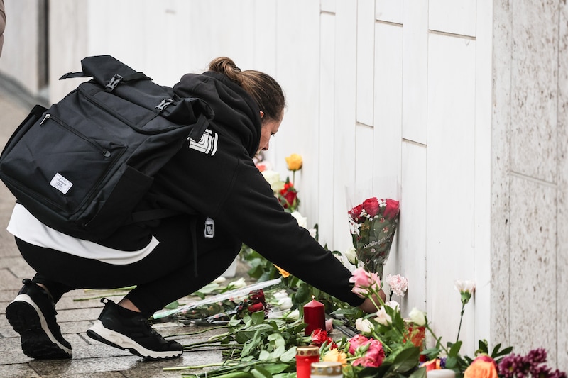 A woman lays flowers at the crime scene after at least two people were killed and several others injured when a car plowed into a crowd in a pedestrian zone in Leipzig, Germany.